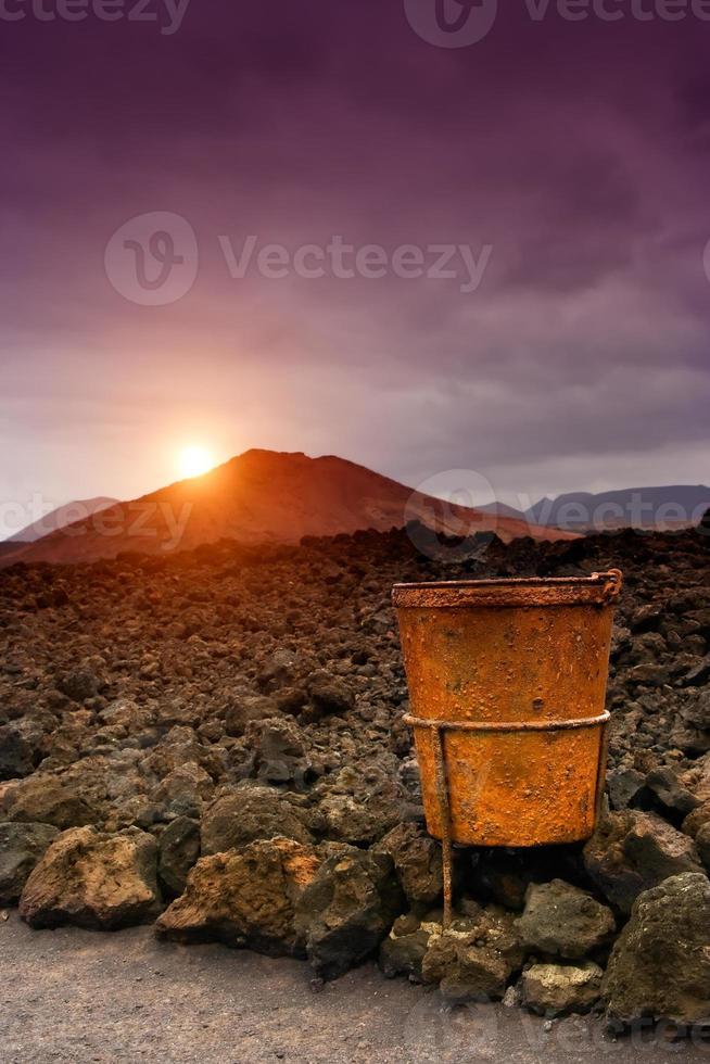 tramonto nel timanfaya con arrugginito metallo cestino nel il primo piano foto