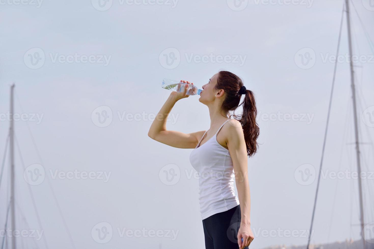 acqua potabile della giovane bella donna dopo l'esercizio di forma fisica foto