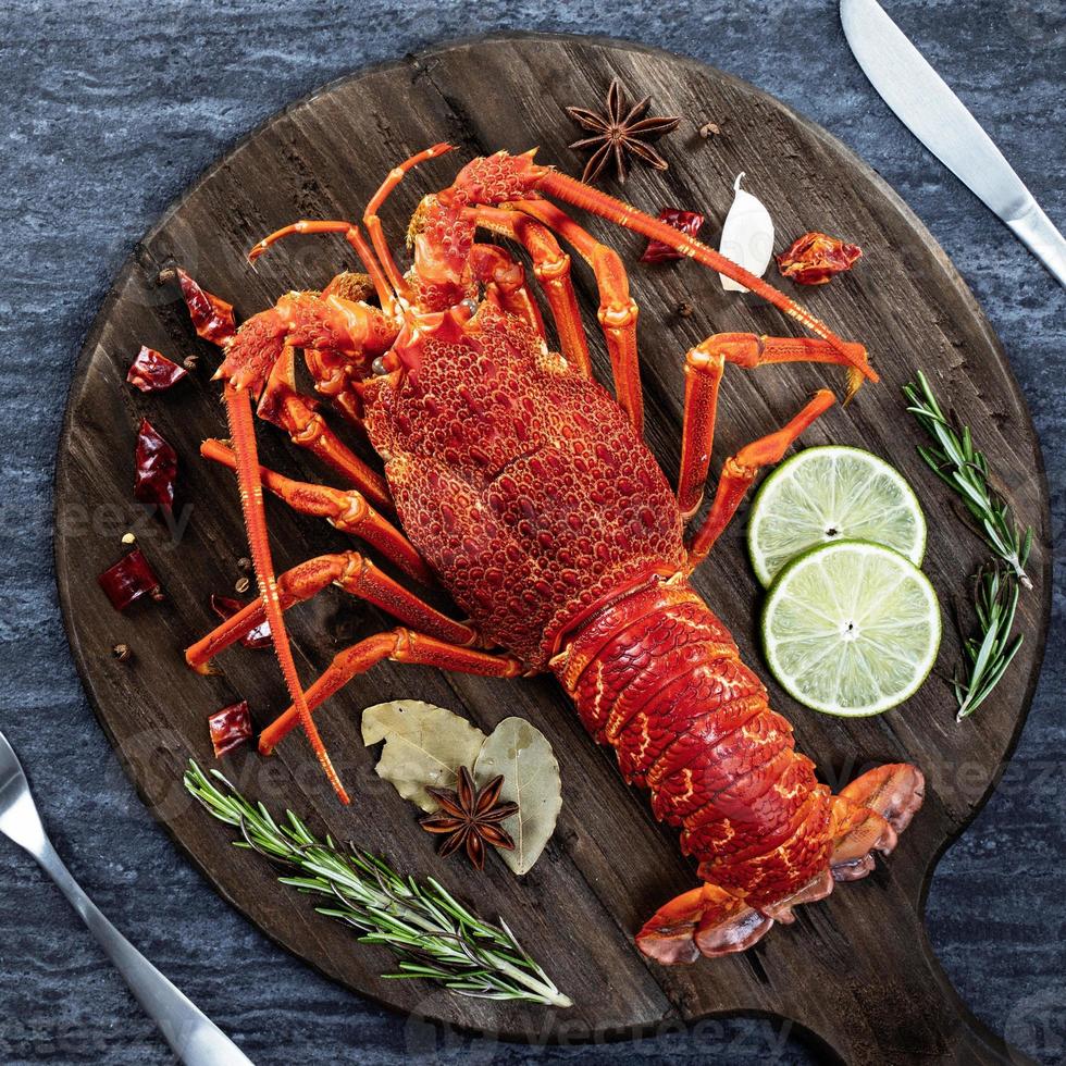 cucinato bollito aragosta, delizioso cena frutti di mare pasto impostato con coltello e forchetta su nero pietra ardesia sfondo, ristorante menù disegno, superiore Visualizza, alto foto