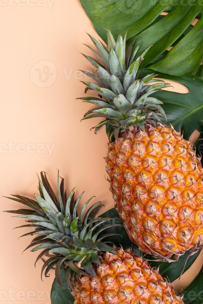 bellissimo ananas su tropicale palma Monstera le foglie isolato su luminosa pastello arancia giallo sfondo, superiore Visualizza, piatto posizione, alto sopra estate frutta. foto