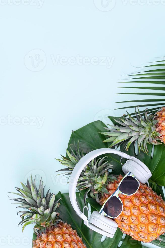 divertente ananas indossare bianca cuffia, concetto di ascoltando musica, isolato su blu sfondo con tropicale palma foglie, superiore Visualizza, piatto posare design. foto