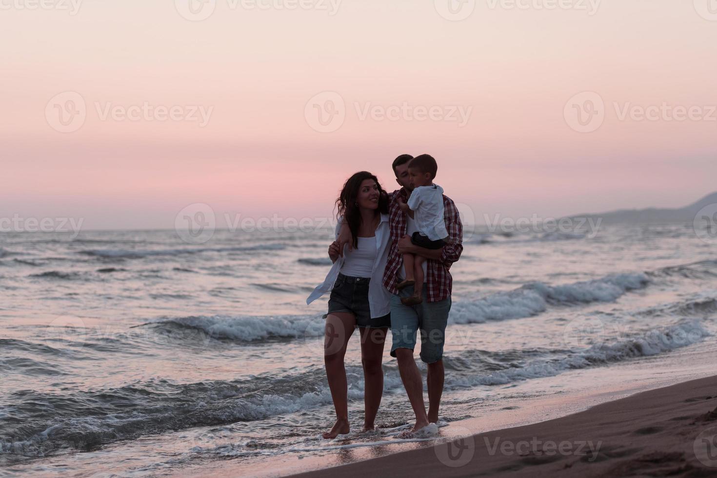 il famiglia gode loro vacanza come essi camminare il sabbioso spiaggia con loro figlio. selettivo messa a fuoco foto