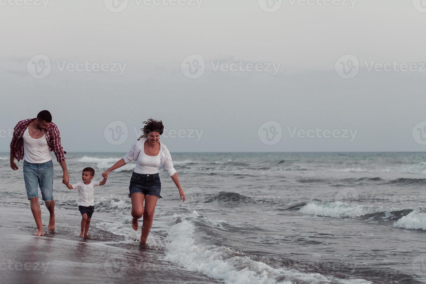 il famiglia gode loro vacanza come essi camminare il sabbioso spiaggia con loro figlio. selettivo messa a fuoco foto