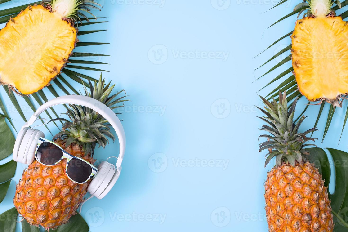 divertente ananas con cuffie bianche, concetto di ascolto di musica, isolato su sfondo colorato con foglie di palma tropicali, vista dall'alto, design piatto. foto