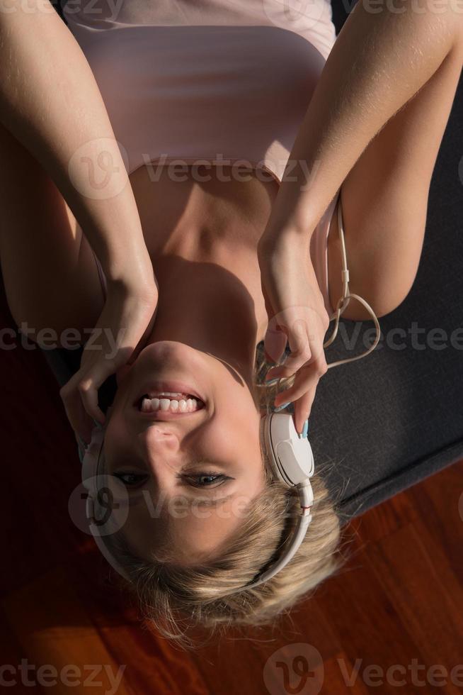 bello biondo donna ascoltando per musica mentre riposo su divano foto