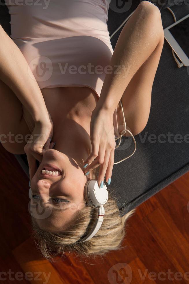 bello biondo donna ascoltando per musica mentre riposo su divano foto