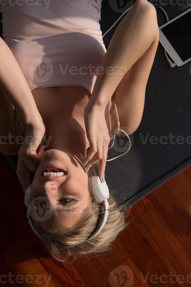 bello biondo donna ascoltando per musica mentre riposo su divano foto