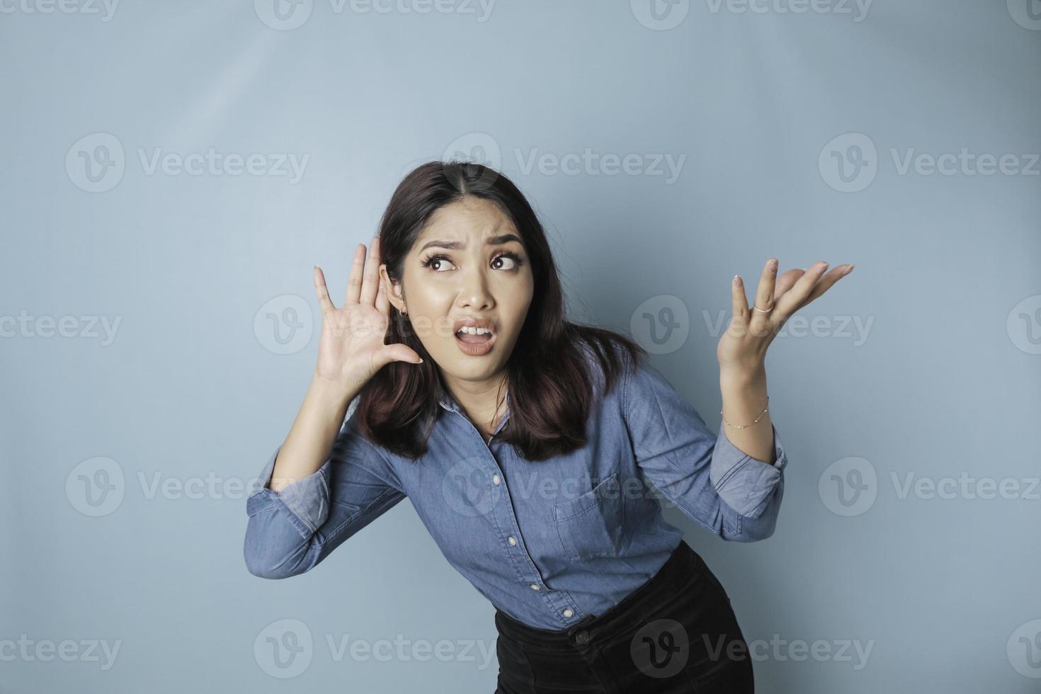 stupito curioso sposa giovane donna indossare un' blu camicia provando per sentire voi origliare ascoltando intensamente isolato su blu turchese sfondo studio ritratto. foto