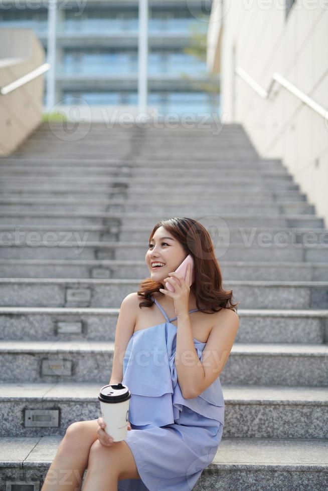 bellissimo donna parlando su smartphone e Tenere carta tazza foto