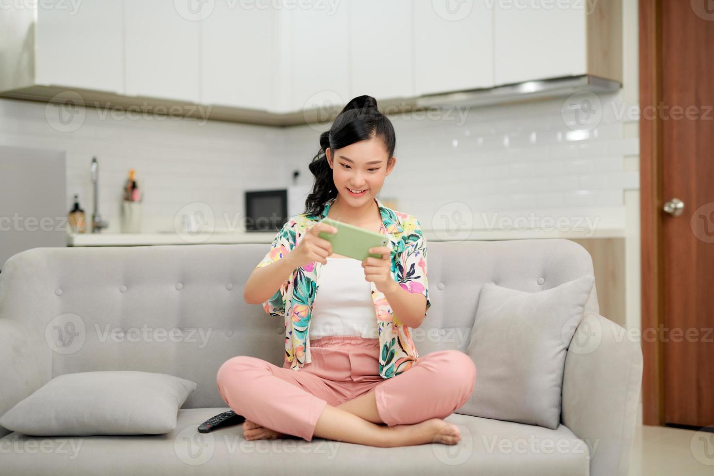 contento giovane donna su divano hold smartphone negozio in linea o dai un'occhiata mobile applicazione o sociale media foto