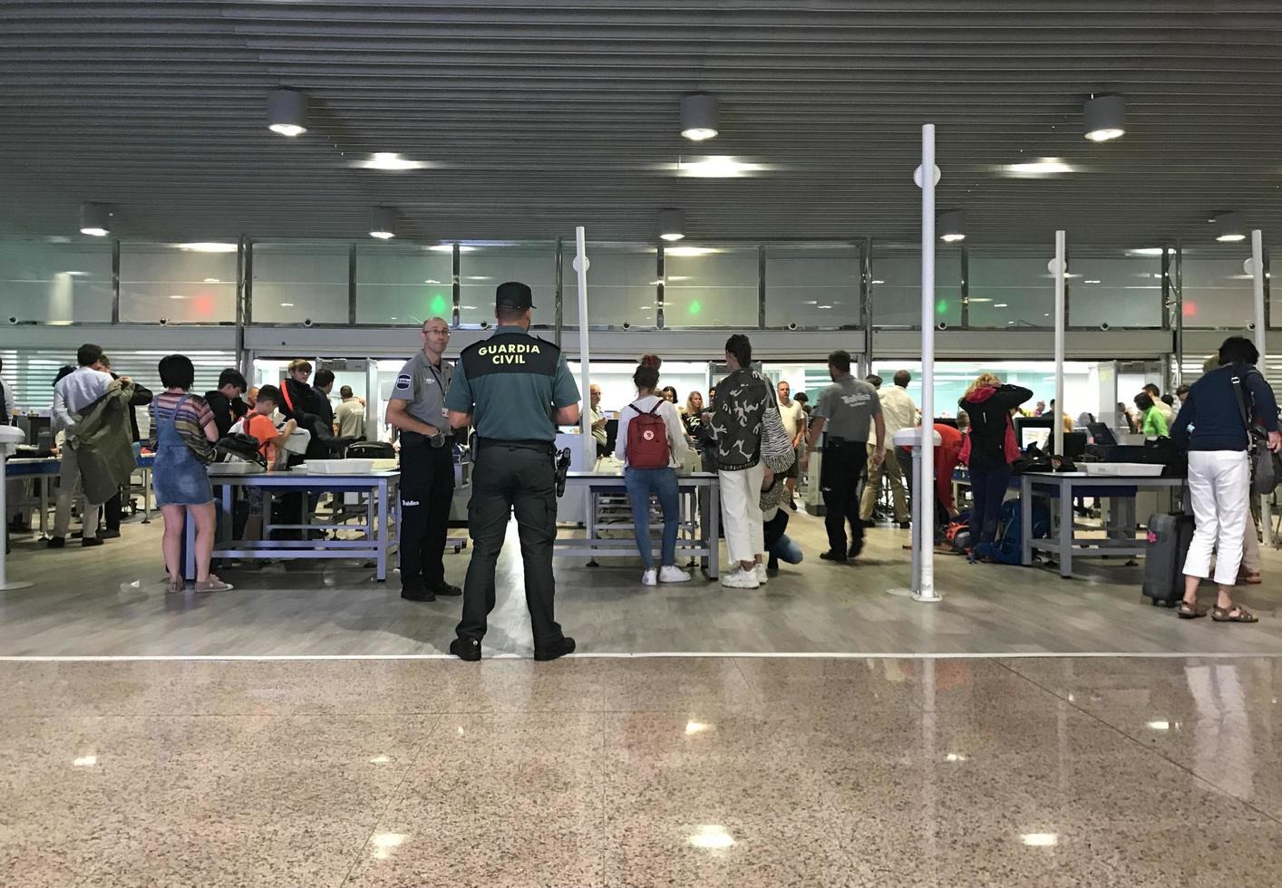 Barcellona, Spagna, 2019 - viaggiatori linea su a il sicurezza dai un'occhiata di Barcellona aeroporto mentre un' sicurezza guardia orologi il scena foto