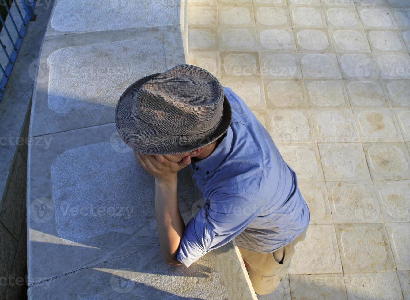 uomo con un' fedora, con il suo testa riposo su il suo mani visto a partire dal un' alto angolo foto