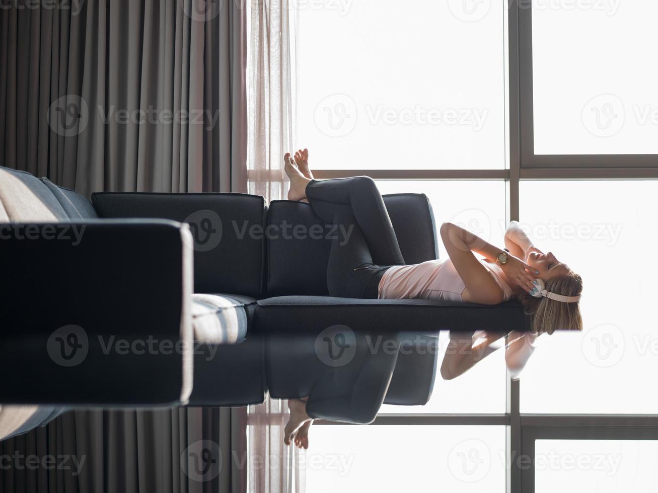 bello biondo donna ascoltando per musica mentre riposo su divano foto