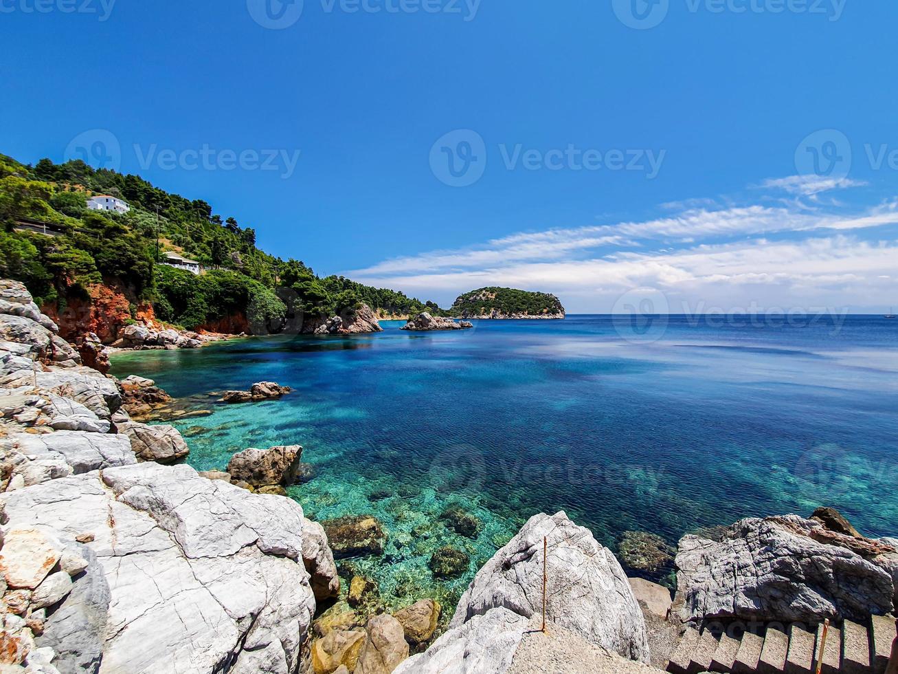 vista incontaminata della baia di un'isola greca con gradini in cemento che conducono all'acqua. foto