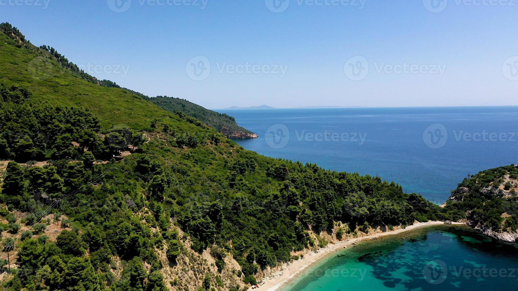 viste aeree dei droni su una costa rocciosa, acque cristalline del Mar Egeo, spiagge turistiche e tanto verde nell'isola di Skopelos, in Grecia. una vista tipica di molte isole greche simili. foto