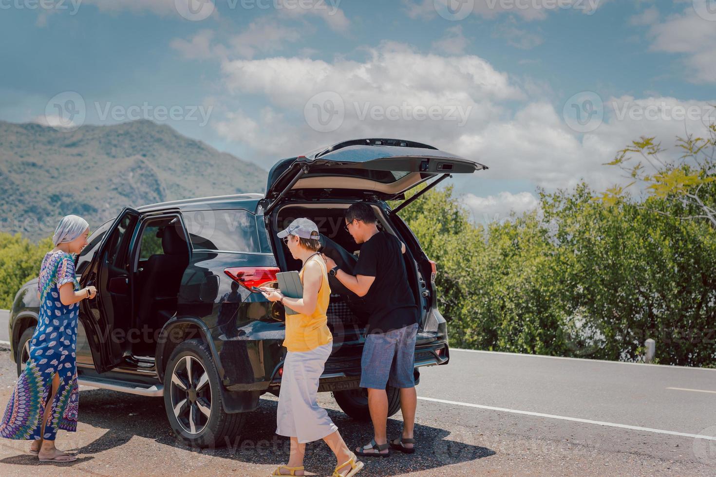 uomo con amici Caricamento in corso bagaglio nel tronco di automobile, in viaggio su estate vacanza. foto