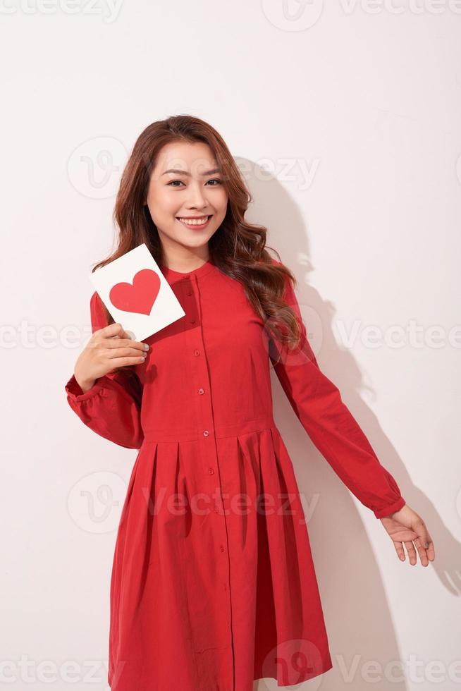ritratto di contento romantico ragazza con rosso carta a forma di cuore cartolina, romantico auguri, San Valentino giorno celebrazione, amore concetto foto