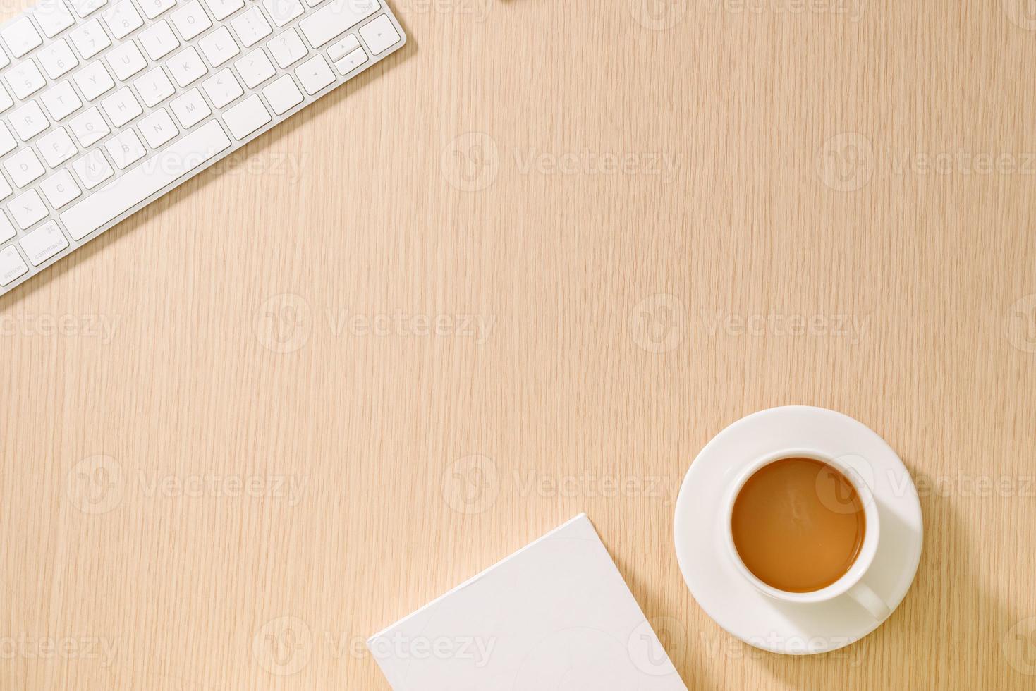 piatto posizione, superiore Visualizza ufficio tavolo scrivania. spazio di lavoro con vuoto Nota prenotare, tastiera del computer, ufficio forniture e caffè tazza su di legno sfondo. foto