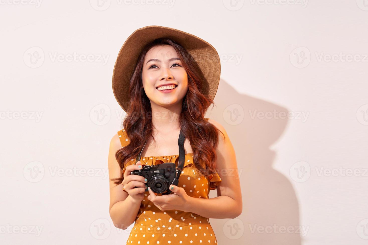 Immagine di giovane fotografo donna isolato al di sopra di beige sfondo parete Tenere telecamera. foto