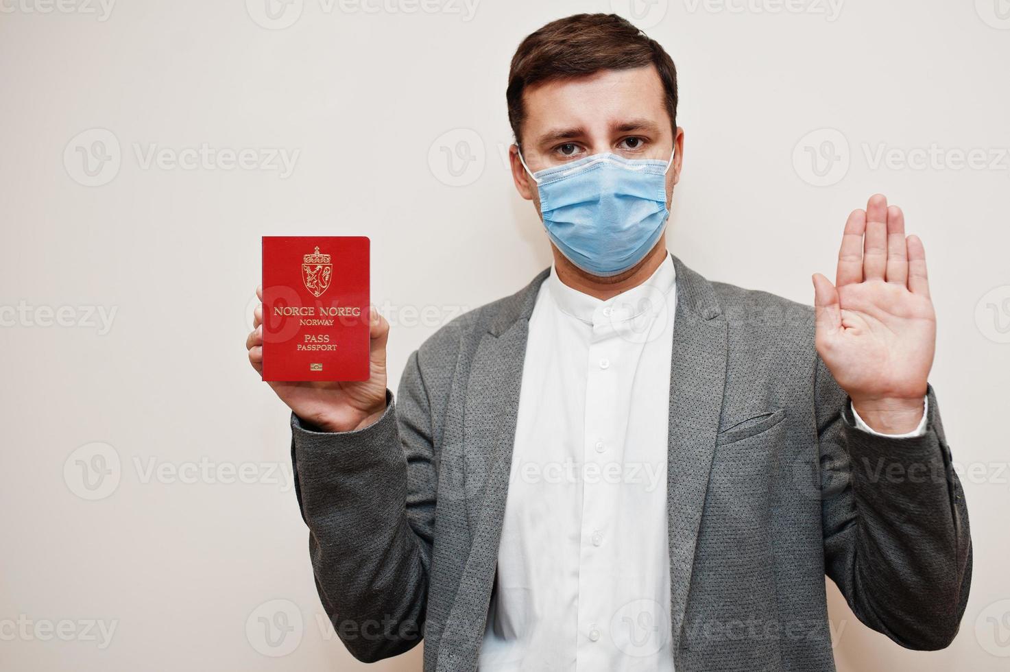 europeo uomo nel formale indossare e viso maschera, mostrare Norvegia passaporto con fermare cartello mano. coronavirus lockdown nel Europa nazione concetto. foto