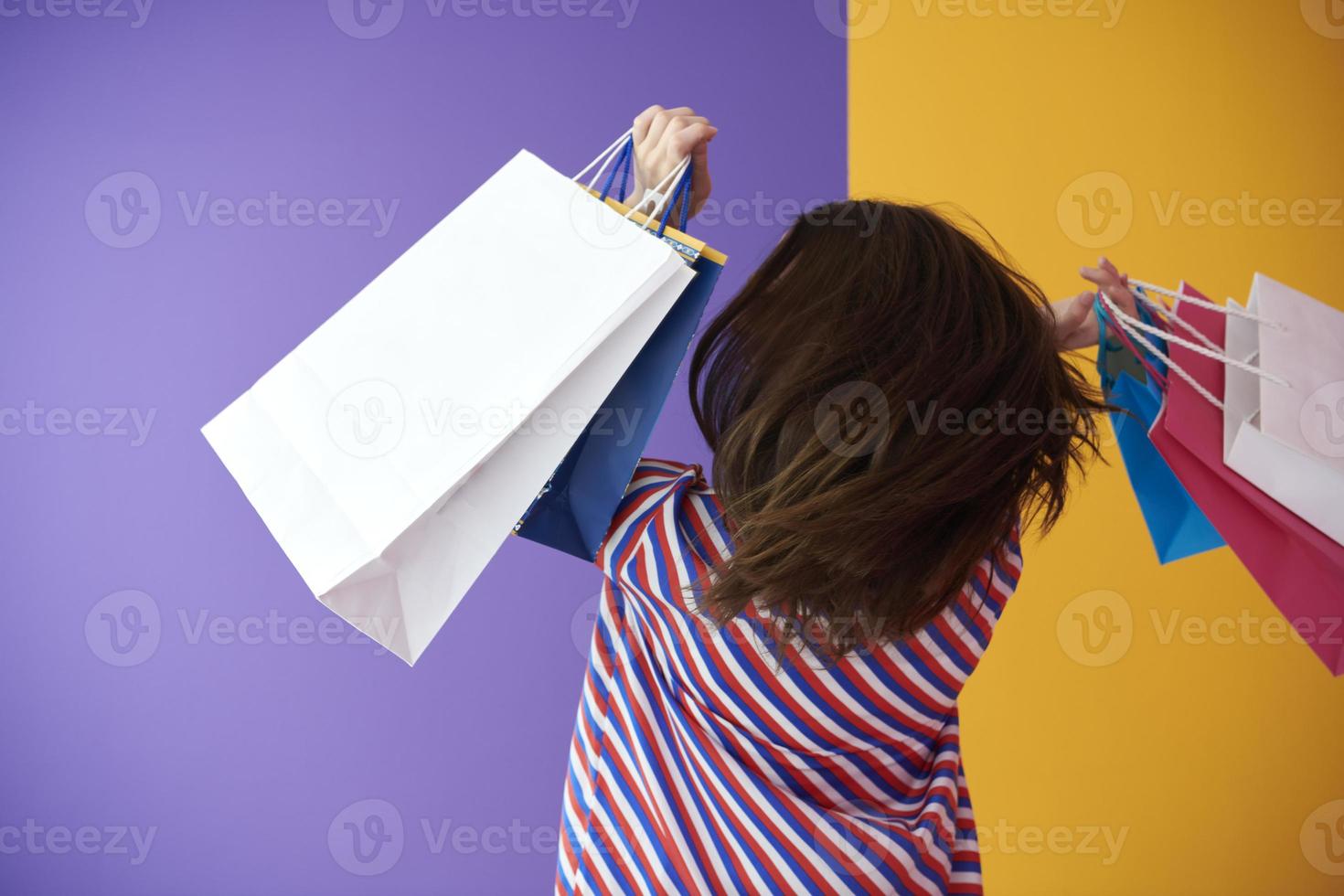 giovane donna con sua indietro trasformato Tenere shopping borse su colorato sfondo foto