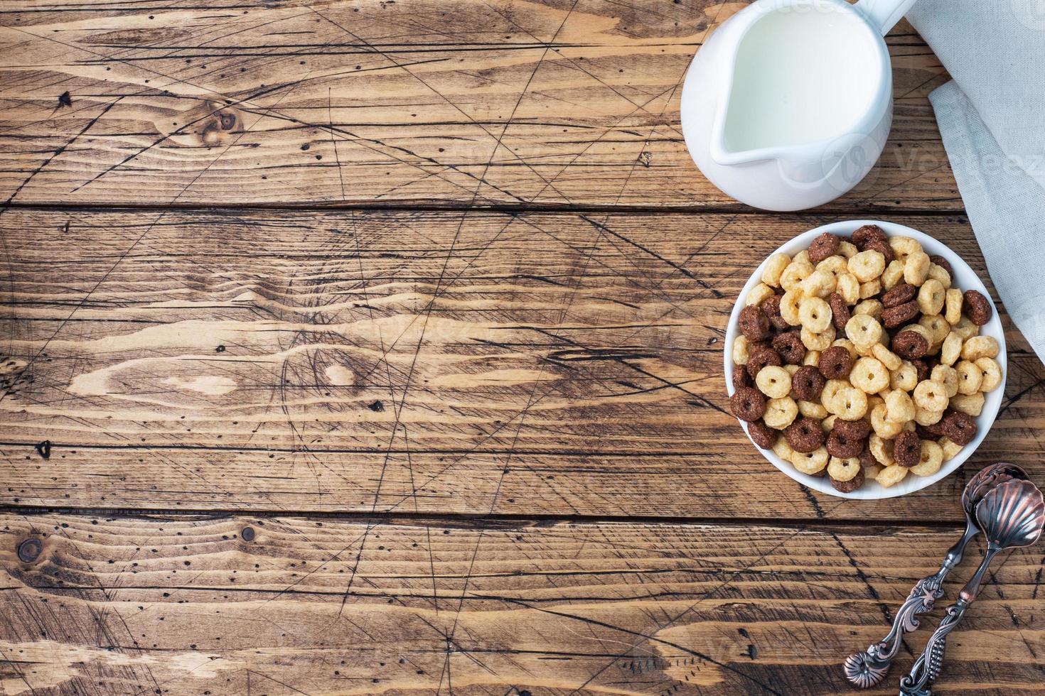 asciutto prima colazione cereali. cioccolato e Mais anelli fatto a partire dal naturale cereali con latte nel un' piatto. di legno rustico sfondo, copia spazio. foto