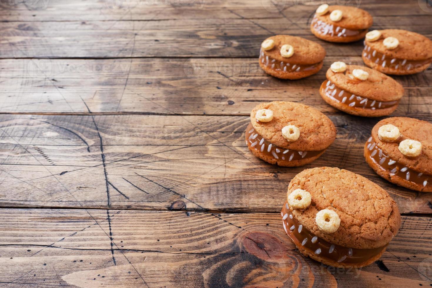 biscotti con pasta di crema a forma di mostri per la festa di halloween. facce buffe fatte in casa fatte di biscotti di farina d'avena e latte condensato bollito. copia spazio foto