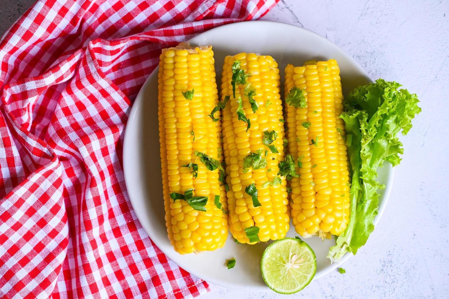 cibo di mais dolce con insalata di verdure lime coriandolo e lattuga, pannocchie di mais mature al vapore o bollite mais dolce per cibo cena o spuntino vegano, mais dolce cotto su sfondo bianco piatto foto