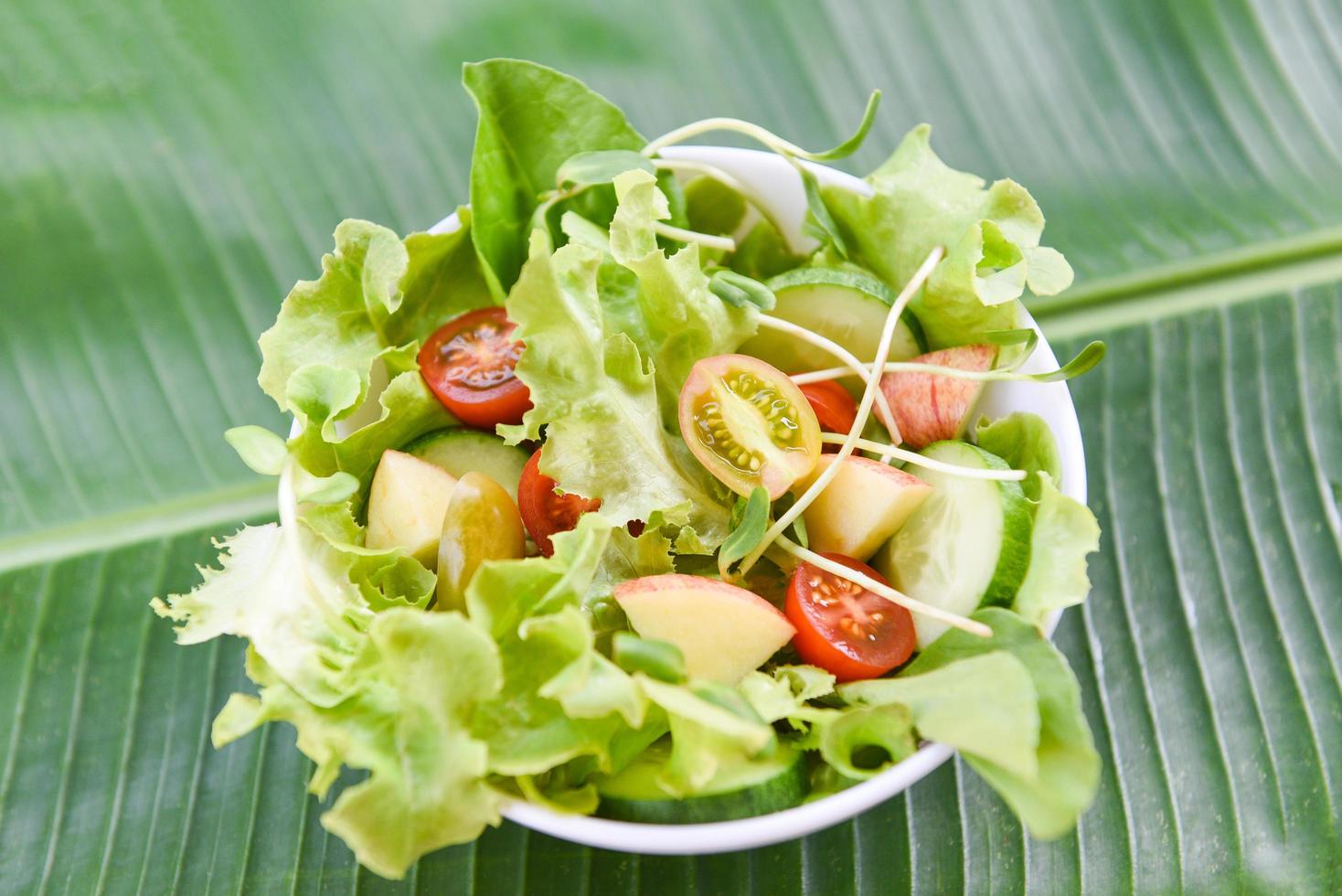 insalata di verdure - insalatiera con frutta e lattuga fresca pomodoro cetriolo su foglia di banana mangiare cibo sano concetto foto