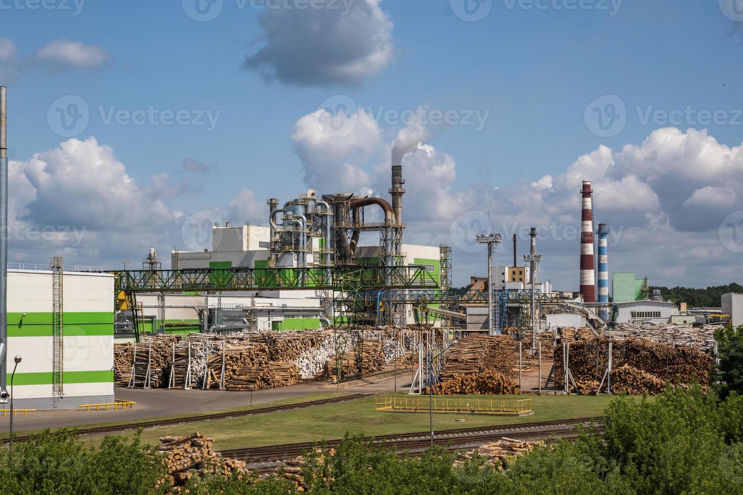 tubi della segheria dell'impianto di impresa di lavorazione del legno vicino al fiume. concetto di inquinamento atmosferico. paesaggio industriale inquinamento ambientale rifiuti di centrale termica foto