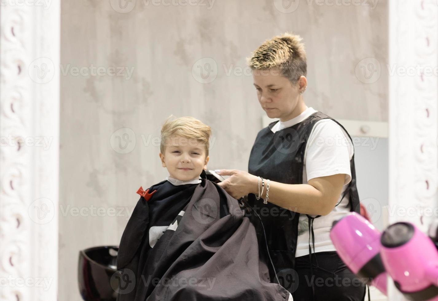 riflessione nel un' specchio di un' ragazzo durante taglio di capelli a barbiere negozio. foto
