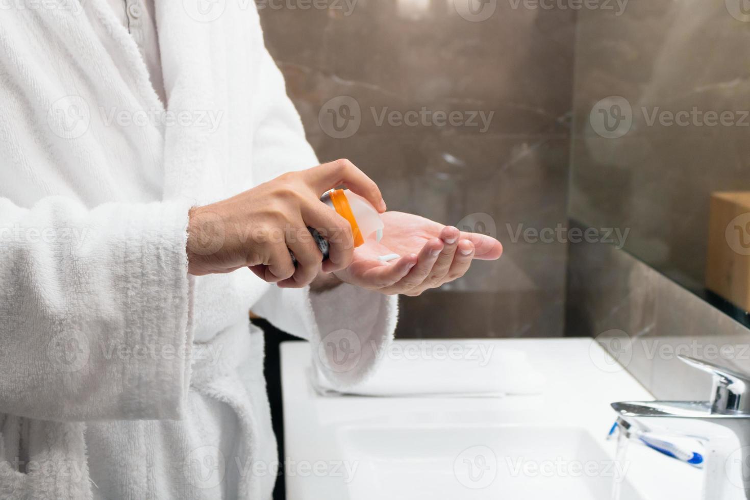 irriconoscibile uomo utilizzando viso crema nel il bagno. foto