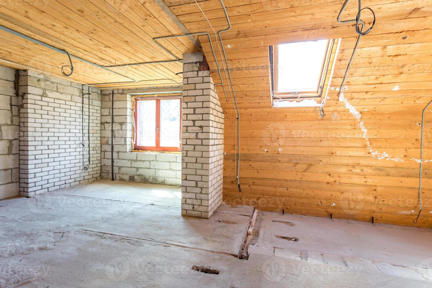 interno vuoto in casa senza riparazione su pavimento in legno mansardato e muro di mattoni foto