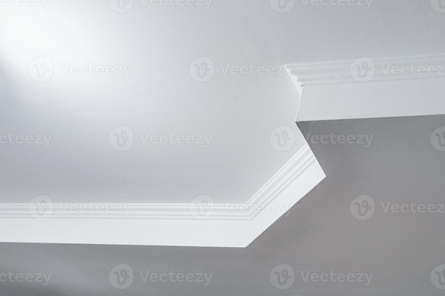 dettaglio di angolo soffitto con intricato corona modanatura. sospeso soffitto e cartongesso costruzione nel vuoto camera nel appartamento o Casa. allungare soffitto bianca e complesso forma. foto