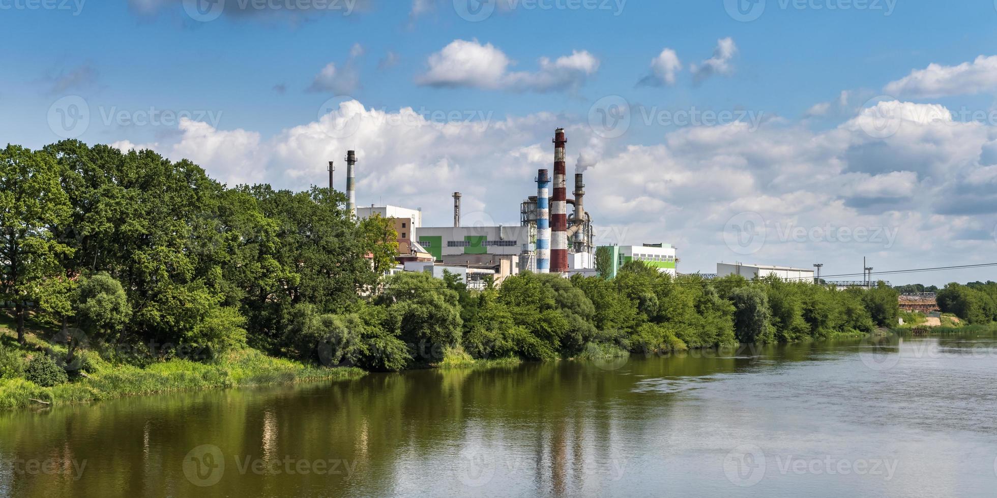 tubi della segheria dell'impianto di impresa di lavorazione del legno vicino al fiume. concetto di inquinamento atmosferico. paesaggio industriale inquinamento ambientale rifiuti di centrale termica foto