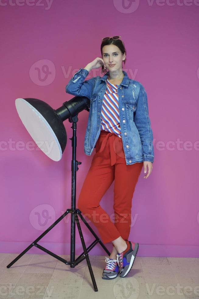 giovane donna pendente contro studio torcia elettrica al di sopra di un' rosa sfondo foto