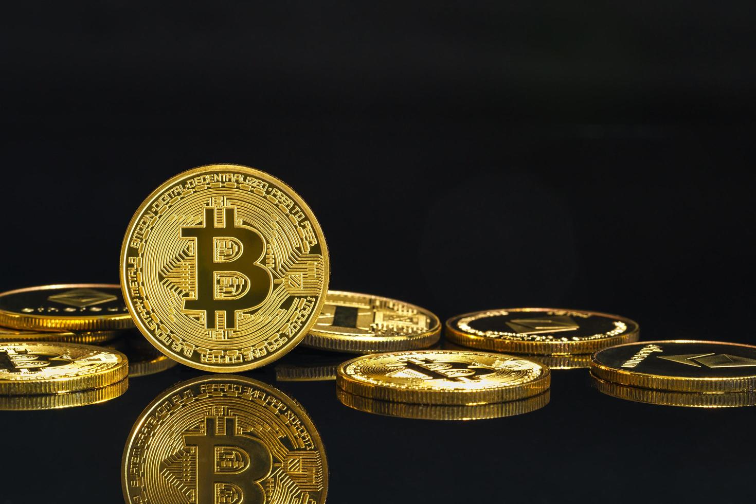 monete d'oro con il simbolo della criptovaluta bitcoin su nero foto