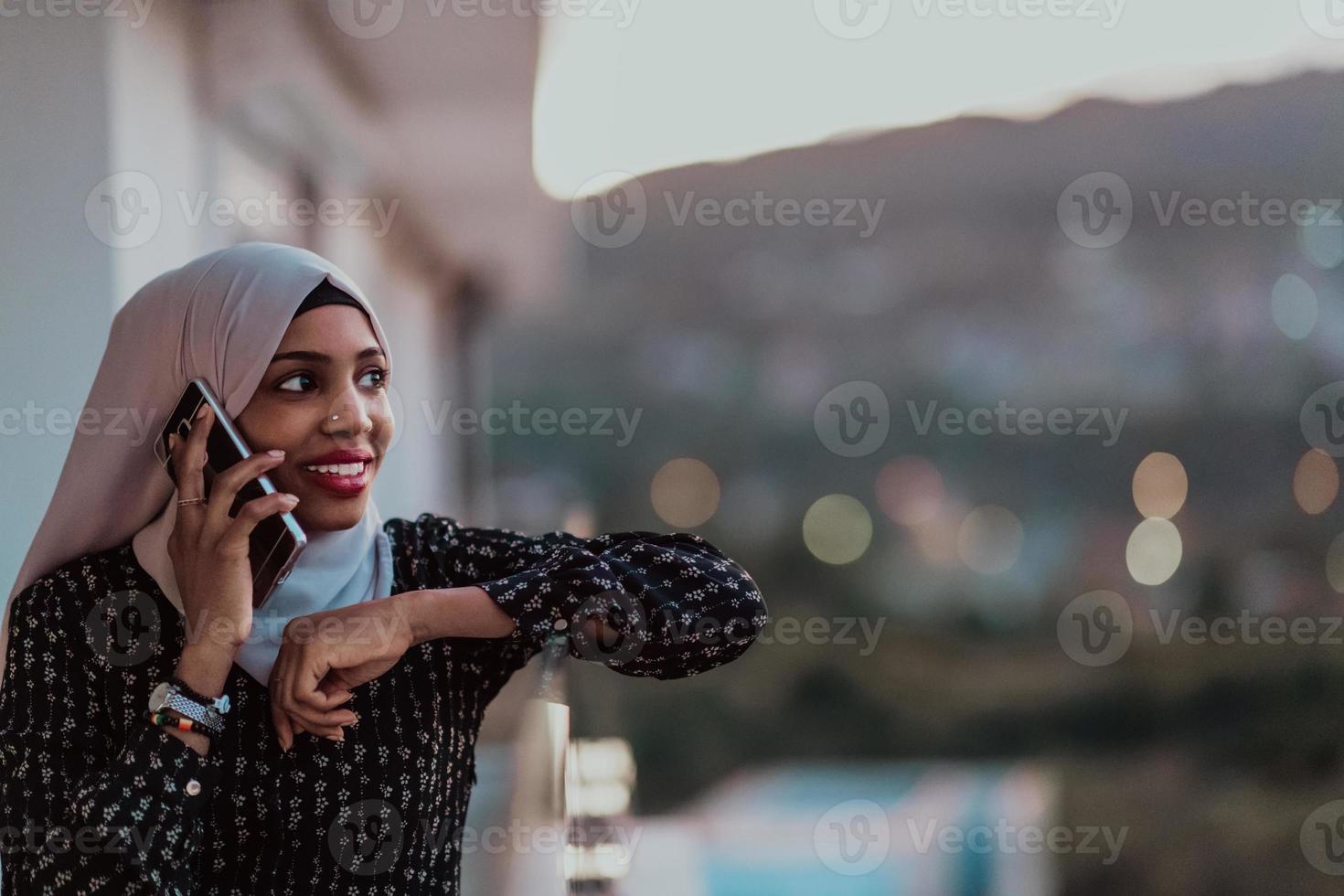 giovane musulmano donna indossare sciarpa velo su urbano città strada a notte sms su un' smartphone con bokeh città leggero nel il sfondo. foto