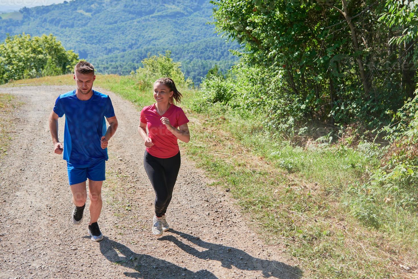 coppia godendo nel un' salutare stile di vita mentre jogging su un' nazione strada foto