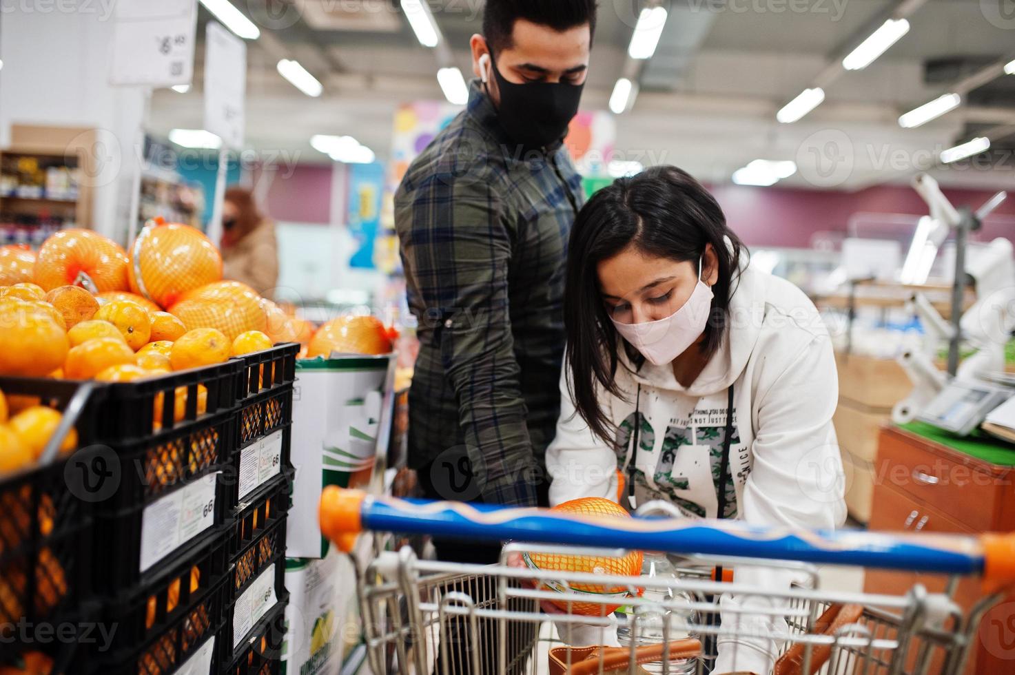 asiatico coppia indossare nel protettivo viso maschera shopping insieme nel supermercato durante pandemia. scegliere pomelo frutta. foto