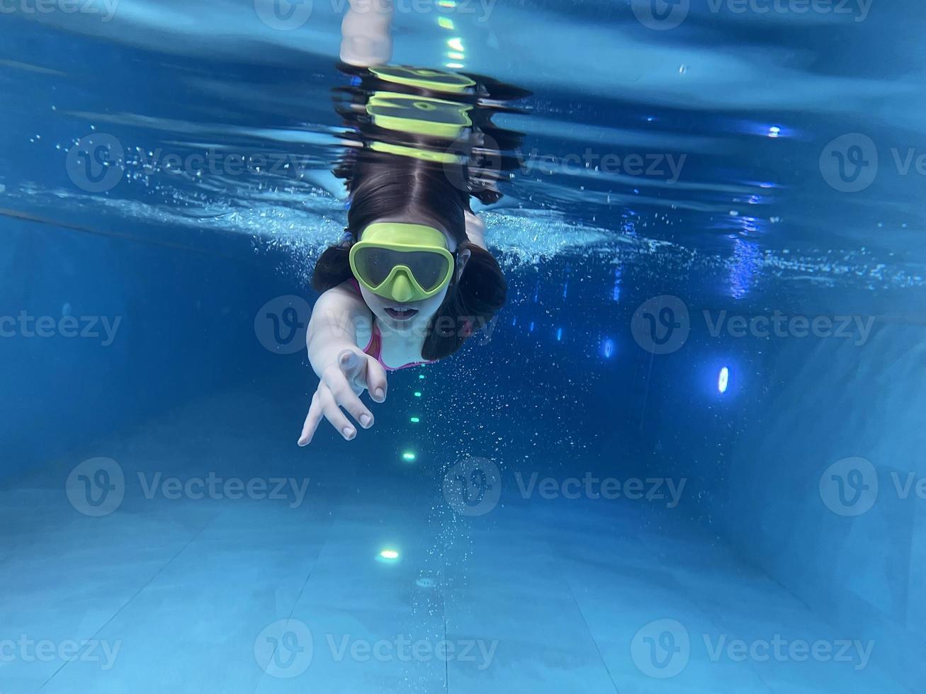 sorridente bambino nel occhiali nuotare, tuffo nel il piscina con divertimento - saltare in profondità giù sott'acqua. salutare stile di vita, persone acqua sport attività su estati. foto