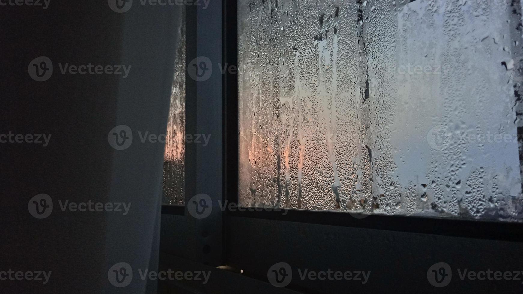 Visualizza a partire dal il finestra nel il freddo mattina con acqua pioggia gocce su bicchiere foto