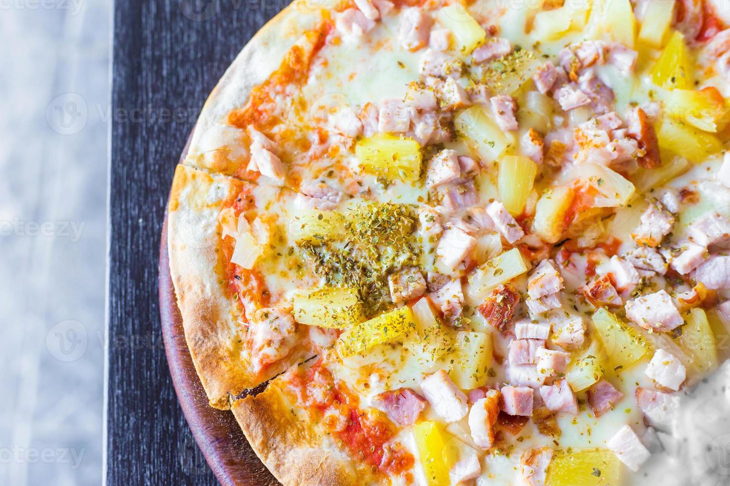 La pizza hawaiana è un alimento italiano preparato con salsa di pomodoro, ananas tritato, prosciutto e formaggio. foto