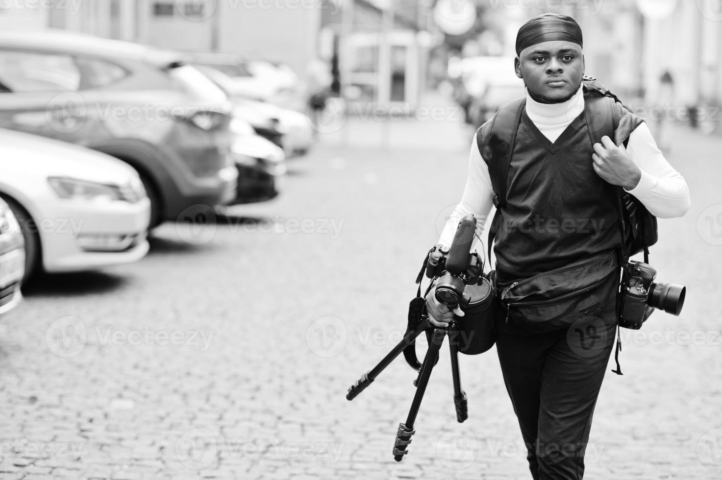 giovane professionale africano americano operatore video Tenere professionale telecamera con tripode professionista attrezzatura. afro cineoperatore indossare nero duraq fabbricazione un' video. foto