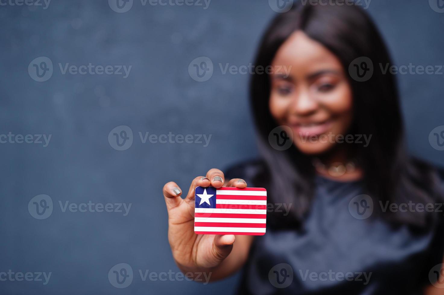orgoglioso per essere liberiano. africano donna hold piccolo Liberia bandiera nel mani. foto
