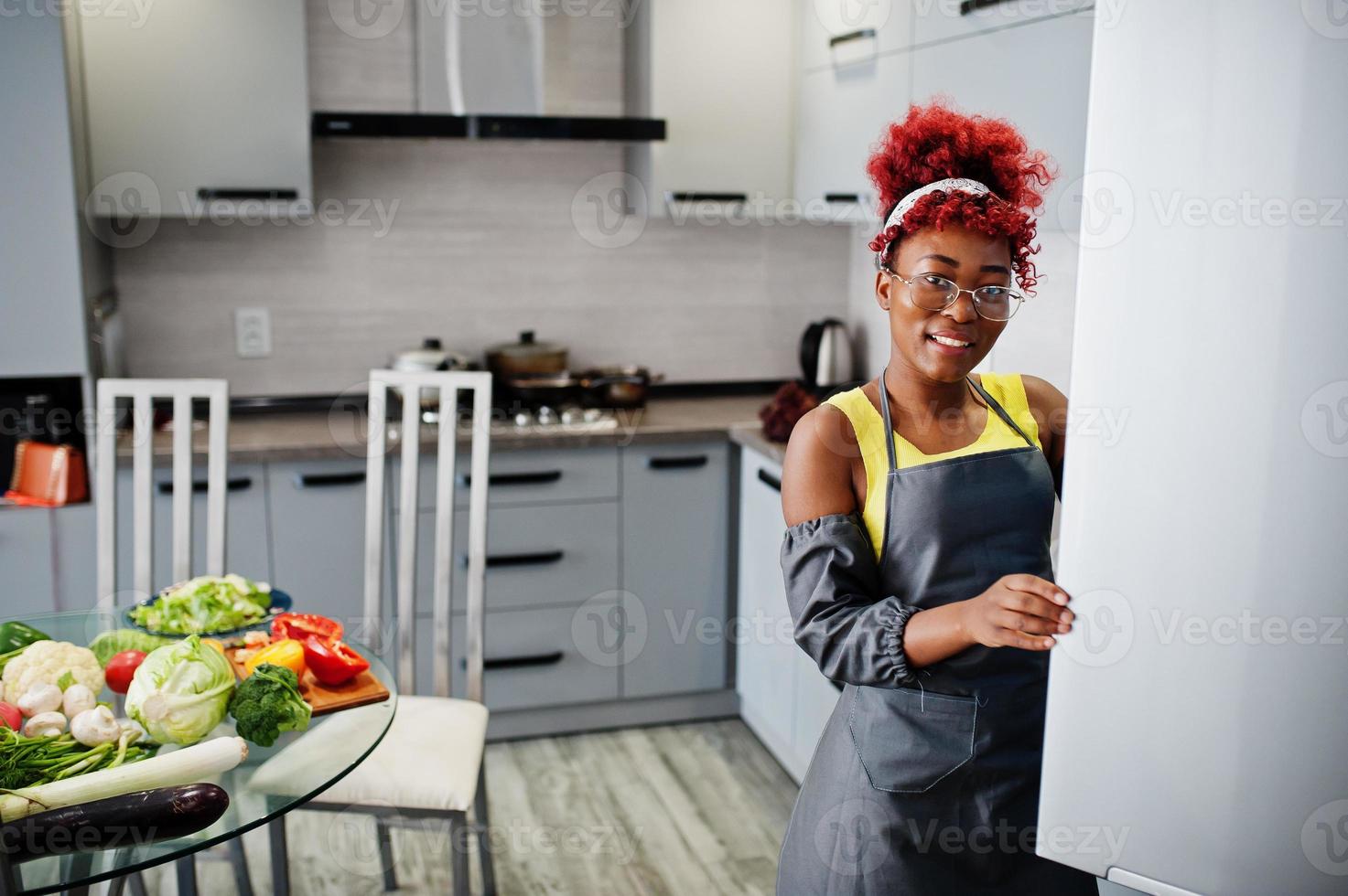 africano americano donna a casa cucina Aperto frigo. foto