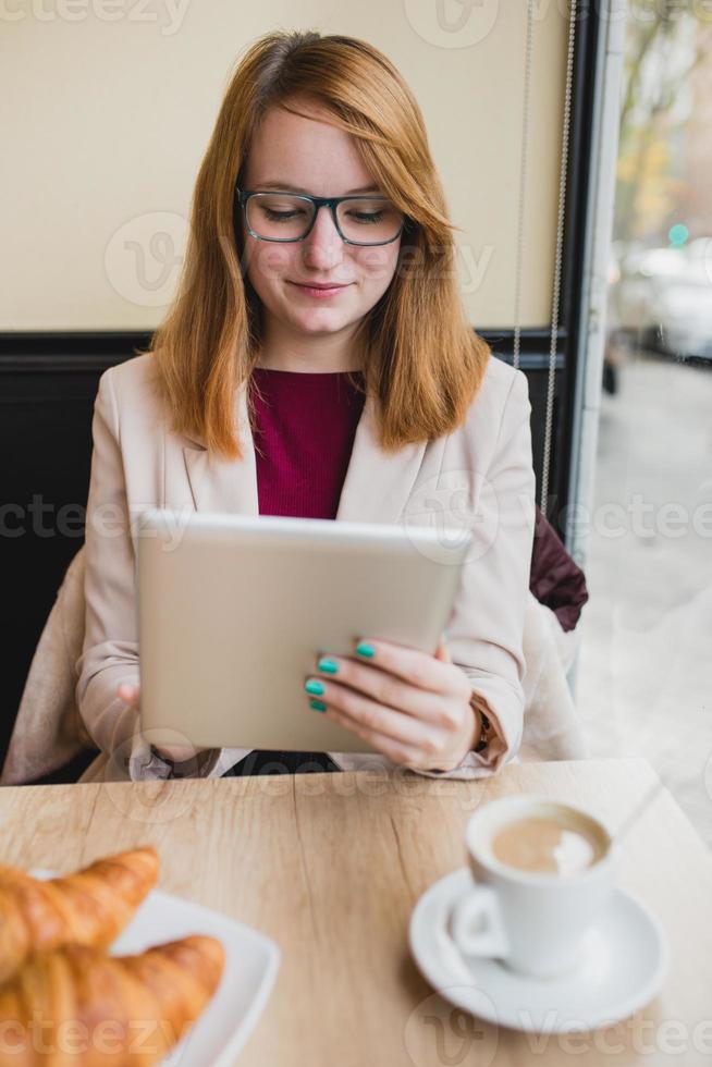 giovane imprenditrice scrivendo sul suo tablet in un negozio di caffè foto