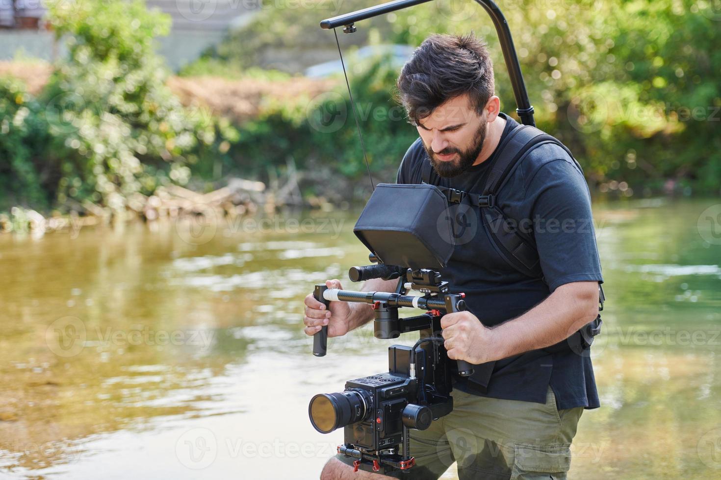 un' professionalmente attrezzata cineoperatore spara nel il acqua circondato di bellissimo natura. foto