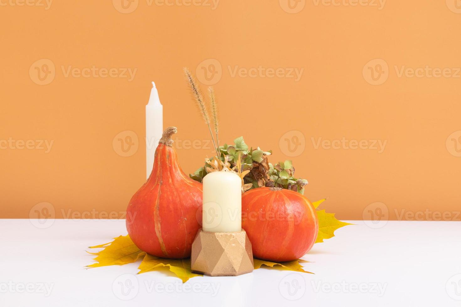 composizione creativa autunnale. ghirlanda di foglie secche, zucche e candela su sfondo bianco arancione. concetto di autunno autunno e giorno del ringraziamento. natura morta foto