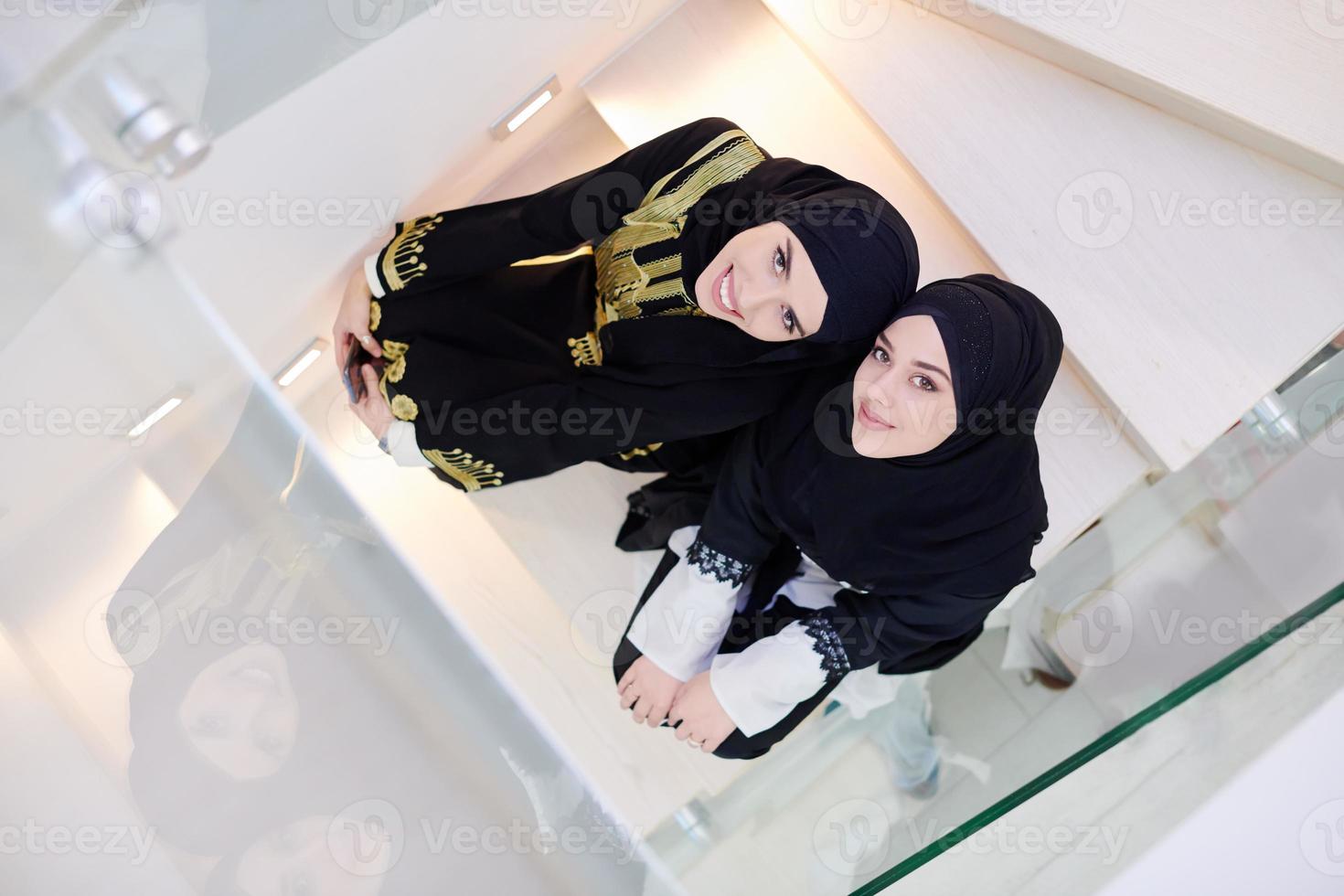 ritratto di bellissimo musulmano donne seduta su di legno le scale a casa foto
